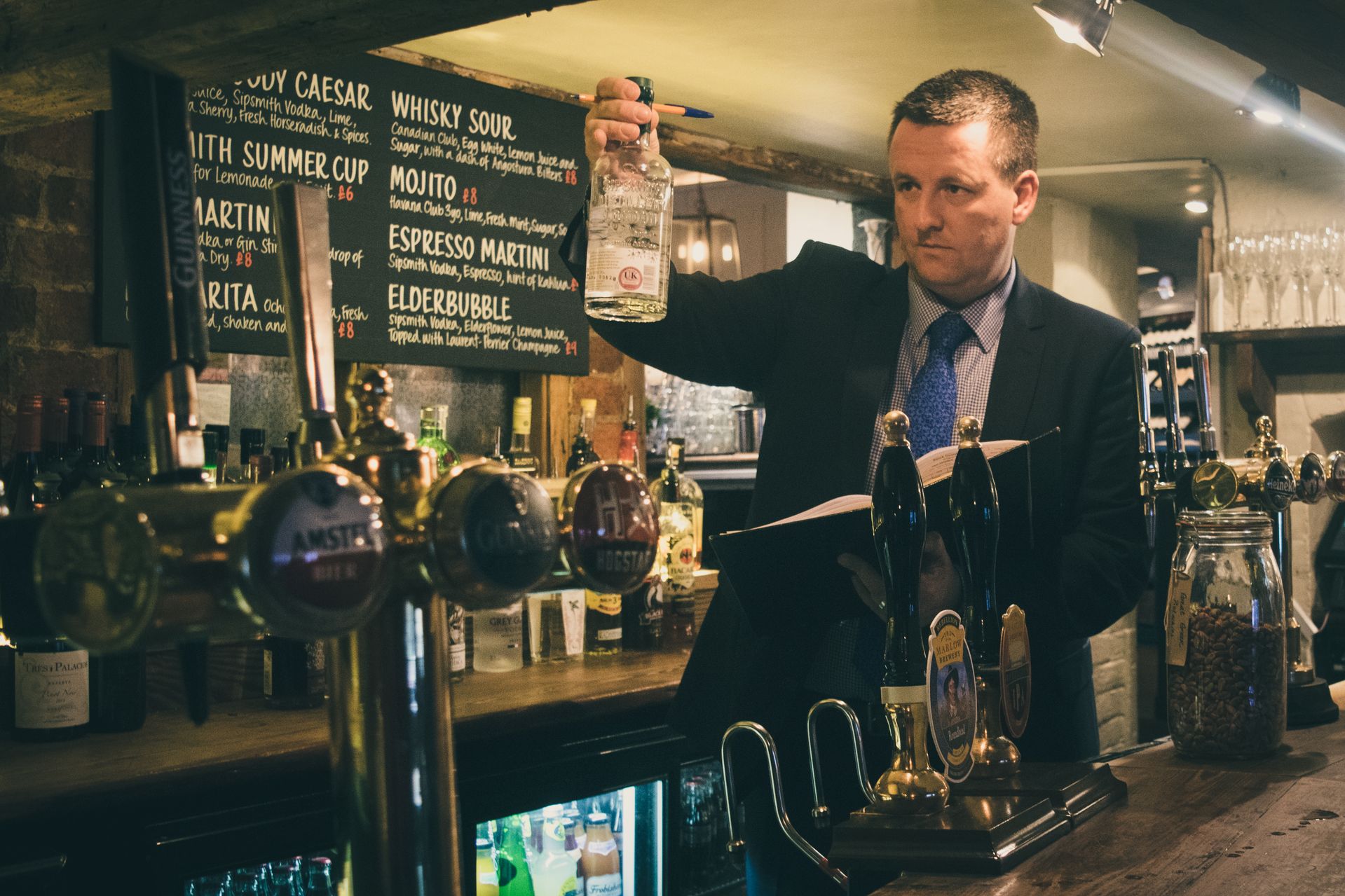 A Venners stocktaker completing a stocktake or stock audit by counting bottles of liquor in a pub.